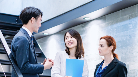 オフィスビルの階段付近で打ち合わせをする多国籍なビジネスパーソン